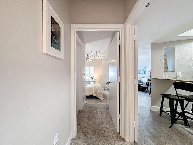 hall with carpet floors, baseboards, wood finished floors, and a textured wall