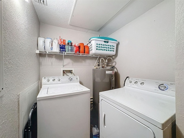 laundry area featuring a textured ceiling, a textured wall, laundry area, washer and dryer, and water heater