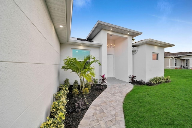 doorway to property with a yard and stucco siding