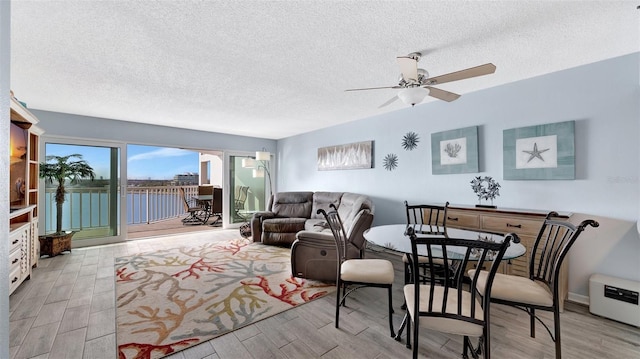 living area with ceiling fan, a textured ceiling, and wood finished floors