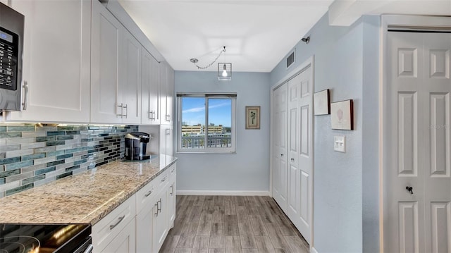 kitchen featuring white cabinetry, baseboards, visible vents, light wood-type flooring, and decorative backsplash