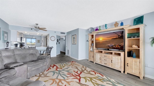 living room with visible vents, a textured ceiling, baseboards, and wood finished floors