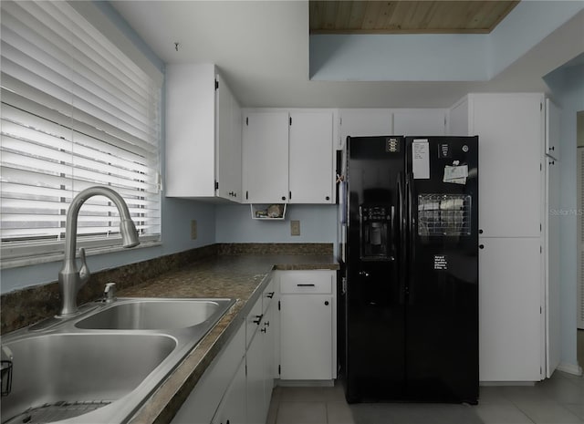 kitchen featuring dark countertops, white cabinets, black refrigerator with ice dispenser, and a sink