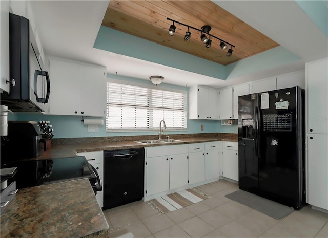 kitchen featuring a tray ceiling, white cabinetry, a sink, and black appliances