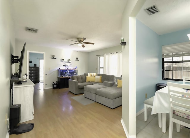 living area with ceiling fan, wood finished floors, visible vents, and baseboards