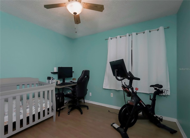 bedroom featuring ceiling fan, a textured ceiling, baseboards, and wood finished floors