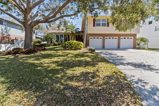 traditional home featuring a garage, driveway, fence, a front lawn, and brick siding