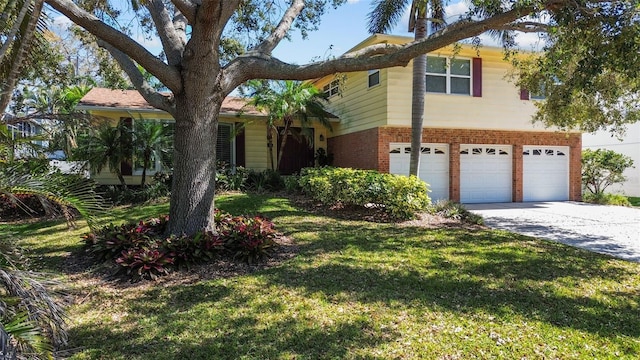 tri-level home with concrete driveway, brick siding, a front lawn, and an attached garage