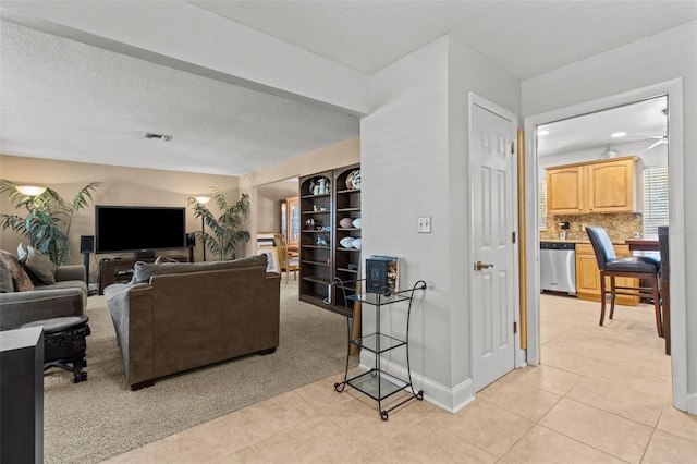 living room with baseboards, visible vents, a textured ceiling, and light tile patterned flooring