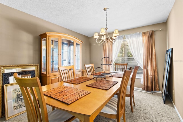 dining space featuring a textured ceiling, an inviting chandelier, baseboards, and light colored carpet