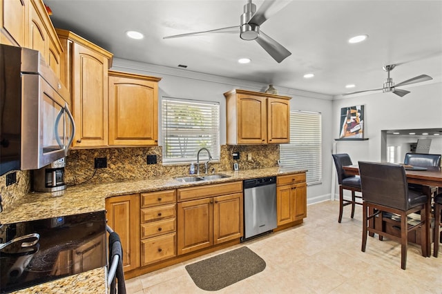 kitchen with ceiling fan, stainless steel appliances, light stone counters, and a sink