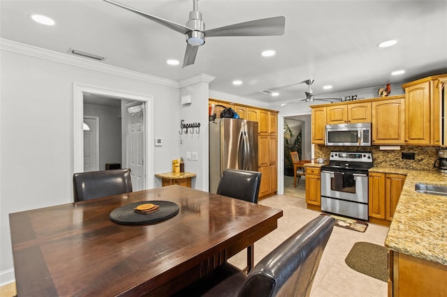 kitchen with light stone counters, decorative backsplash, appliances with stainless steel finishes, ornamental molding, and ceiling fan