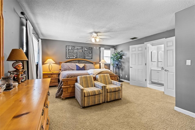 bedroom with a textured ceiling, ensuite bathroom, light carpet, visible vents, and baseboards