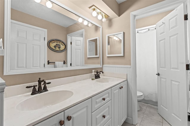 full bathroom featuring double vanity, wainscoting, a sink, and tile patterned flooring