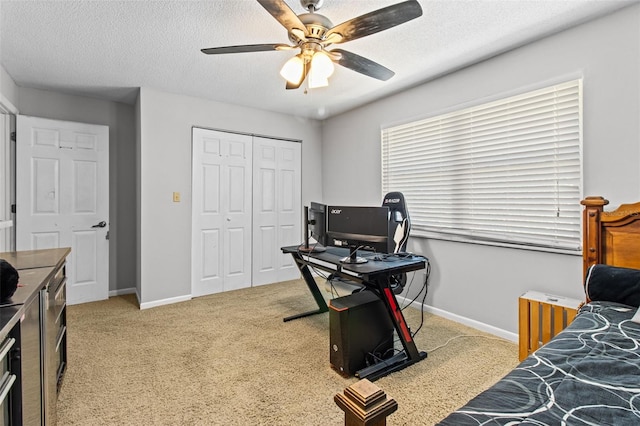 bedroom with a closet, light colored carpet, a textured ceiling, and baseboards