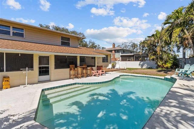 view of pool with a bar, fence, a fenced in pool, and a patio