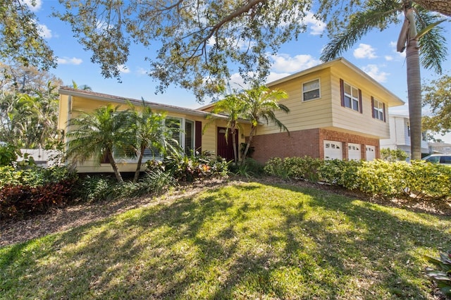 split level home with brick siding, an attached garage, and a front lawn