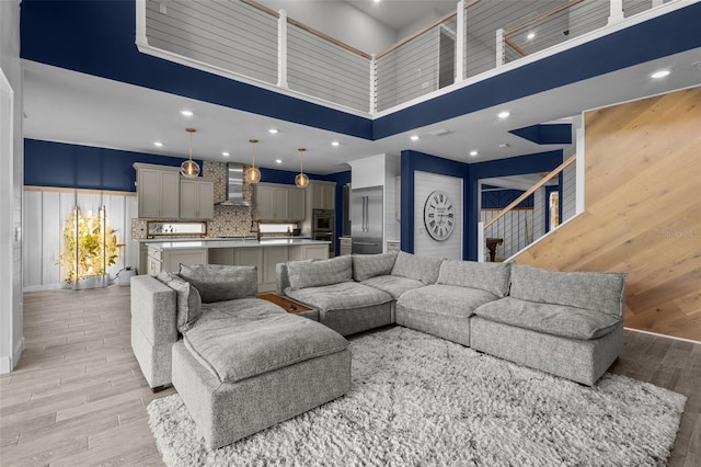 living area featuring light wood-style floors, recessed lighting, a high ceiling, and wood walls