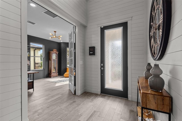 entrance foyer featuring light wood-type flooring, visible vents, and a notable chandelier