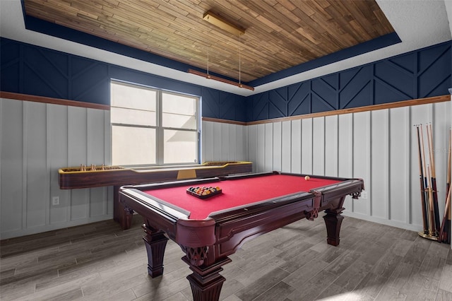 rec room with a tray ceiling, pool table, a decorative wall, wood ceiling, and wood finished floors