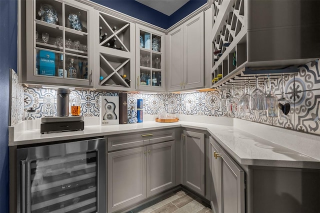 bar with wood finish floors, beverage cooler, backsplash, and a bar