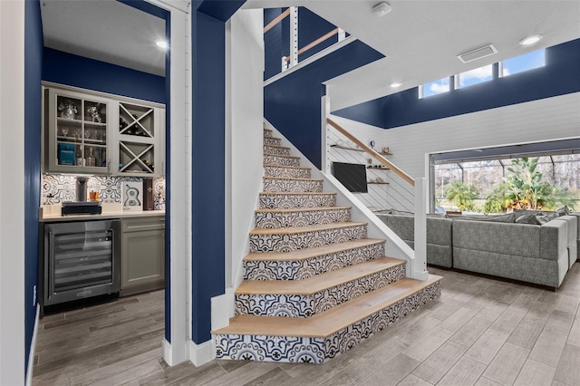 stairs featuring a bar, wine cooler, visible vents, and wood finished floors