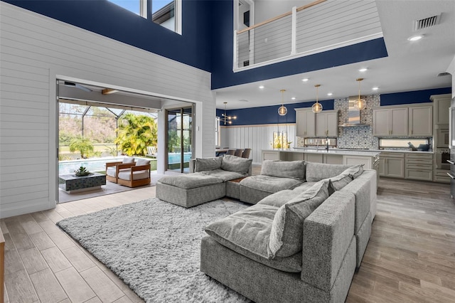 living area featuring light wood-style flooring, a high ceiling, visible vents, and recessed lighting