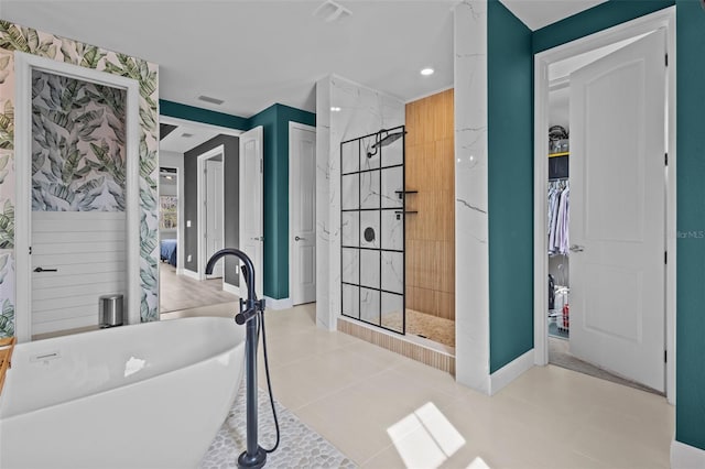 bathroom with a soaking tub, a tile shower, and baseboards