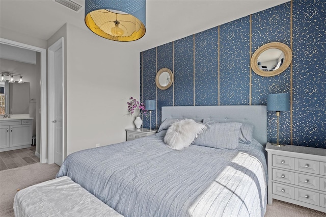 carpeted bedroom featuring visible vents and connected bathroom