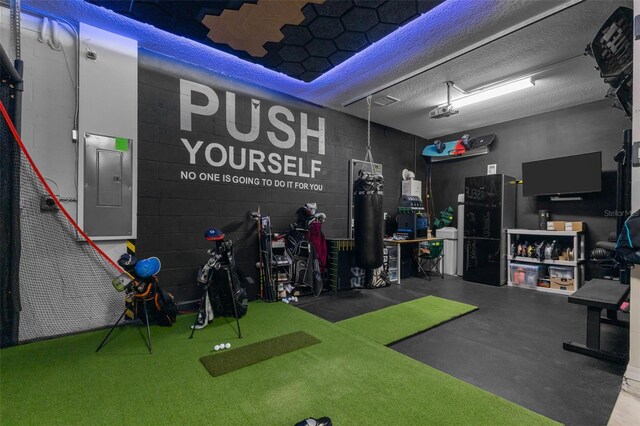 recreation room featuring electric panel, concrete floors, and a textured ceiling