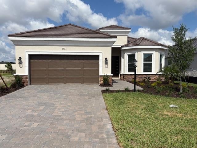 3583 Santa Caterina Blvd, Bradenton, FL 34211 - view of front of home with decorative driveway, a garage, a front lawn, and stucco siding