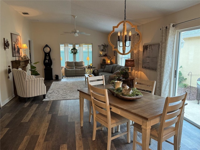 dining area with lofted ceiling, visible vents, dark wood-type flooring, baseboards, and ceiling fan with notable chandelier