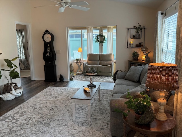 living room featuring dark wood-type flooring, lofted ceiling, baseboards, and a ceiling fan