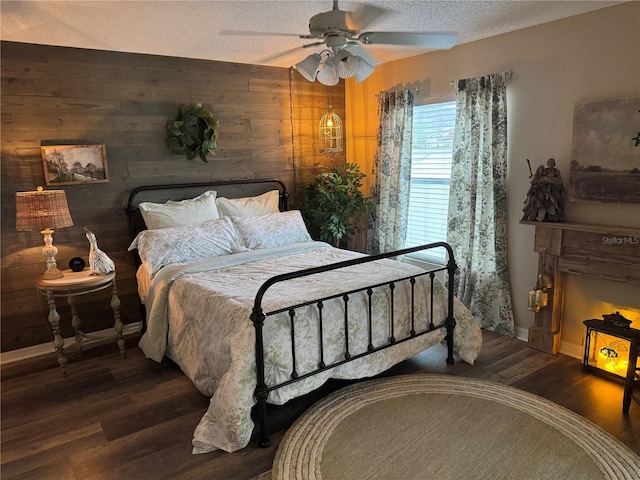 bedroom with a textured ceiling, ceiling fan, wood walls, wood finished floors, and baseboards