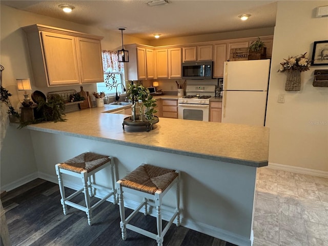 kitchen featuring a peninsula, white appliances, light countertops, and pendant lighting