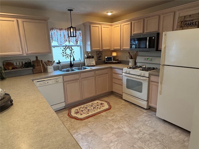 kitchen with white appliances, a sink, light countertops, light brown cabinetry, and pendant lighting