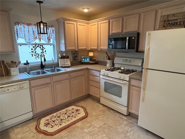 kitchen featuring white appliances, a textured ceiling, light countertops, and a sink