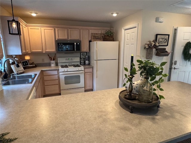 kitchen featuring white appliances, decorative light fixtures, light countertops, light brown cabinets, and a sink