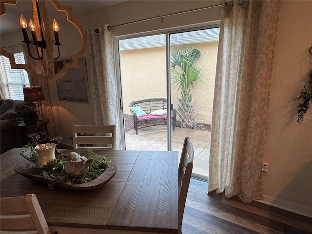 dining space with a chandelier, plenty of natural light, baseboards, and wood finished floors