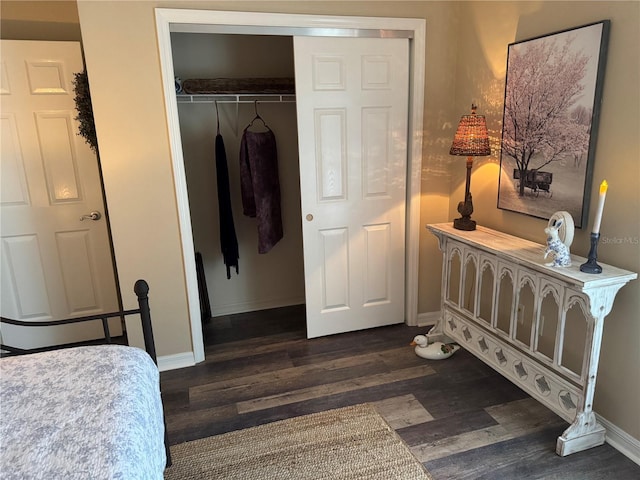 bedroom featuring dark wood-type flooring, a closet, and baseboards