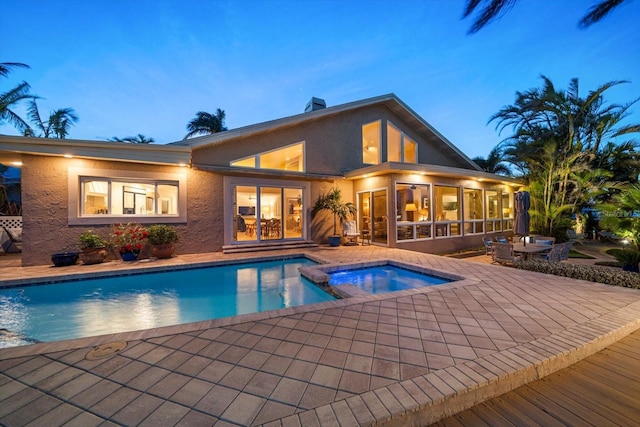 view of swimming pool featuring a patio area, a pool with connected hot tub, and a sunroom