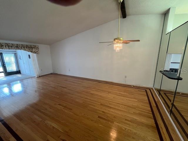 unfurnished living room with vaulted ceiling with beams, ceiling fan, and wood finished floors