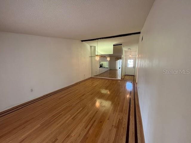 unfurnished living room with a textured ceiling and wood finished floors