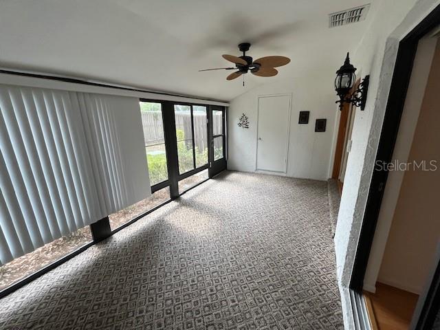 spare room with lofted ceiling, ceiling fan, and visible vents