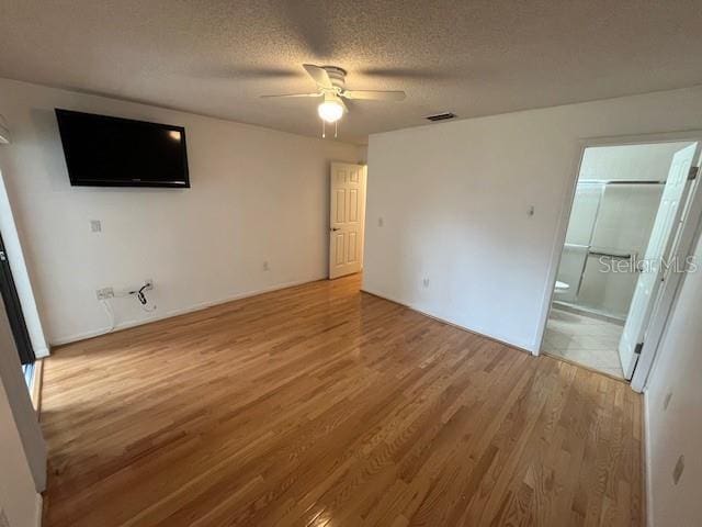 interior space featuring ceiling fan, a textured ceiling, visible vents, and wood finished floors