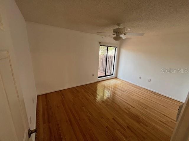 empty room featuring a textured ceiling, ceiling fan, and wood finished floors