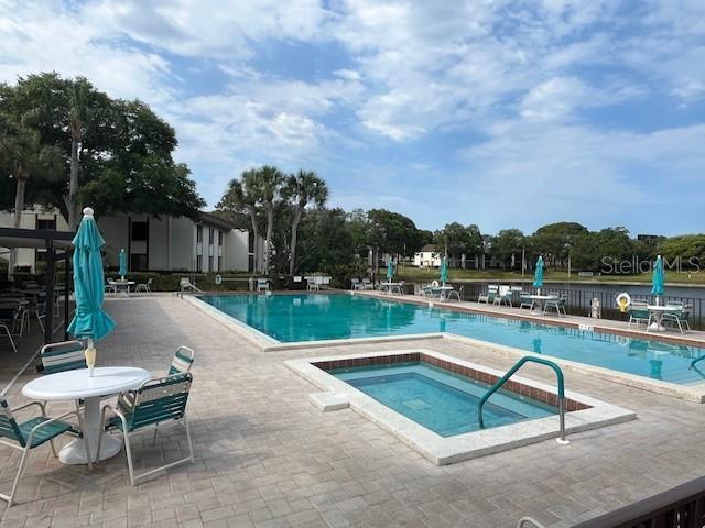 community pool with a hot tub and a patio