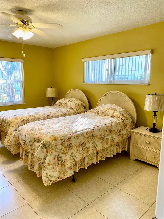 bedroom featuring ceiling fan, a textured ceiling, and light tile patterned flooring