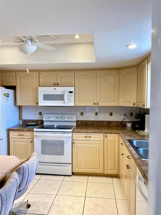 kitchen featuring white appliances, a sink, decorative backsplash, light brown cabinetry, and dark countertops