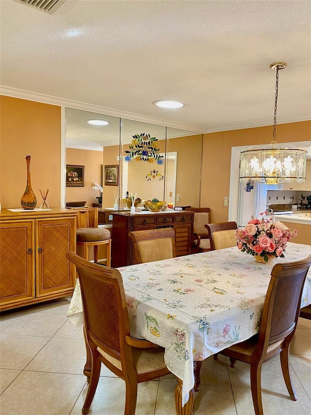 dining area with light tile patterned floors, visible vents, ornamental molding, and a textured ceiling